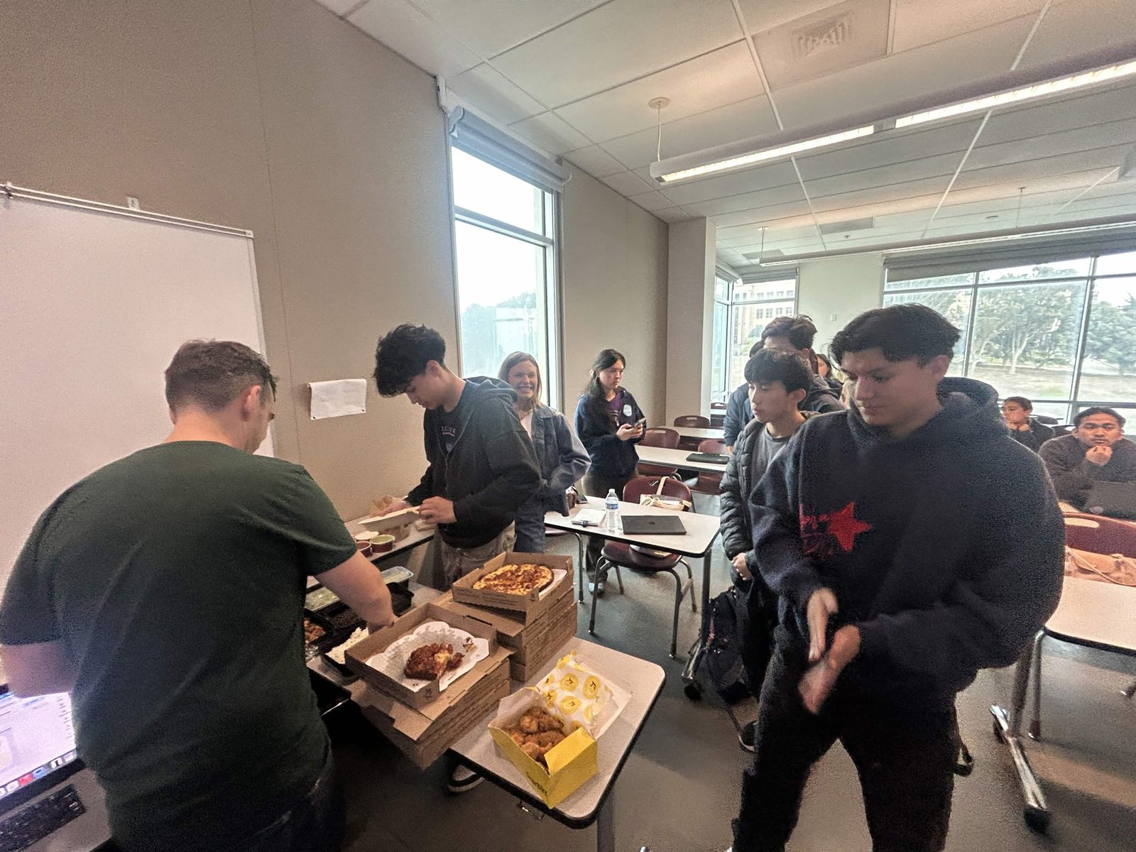 Members line up for pizza and food that Luke brought for the meeting