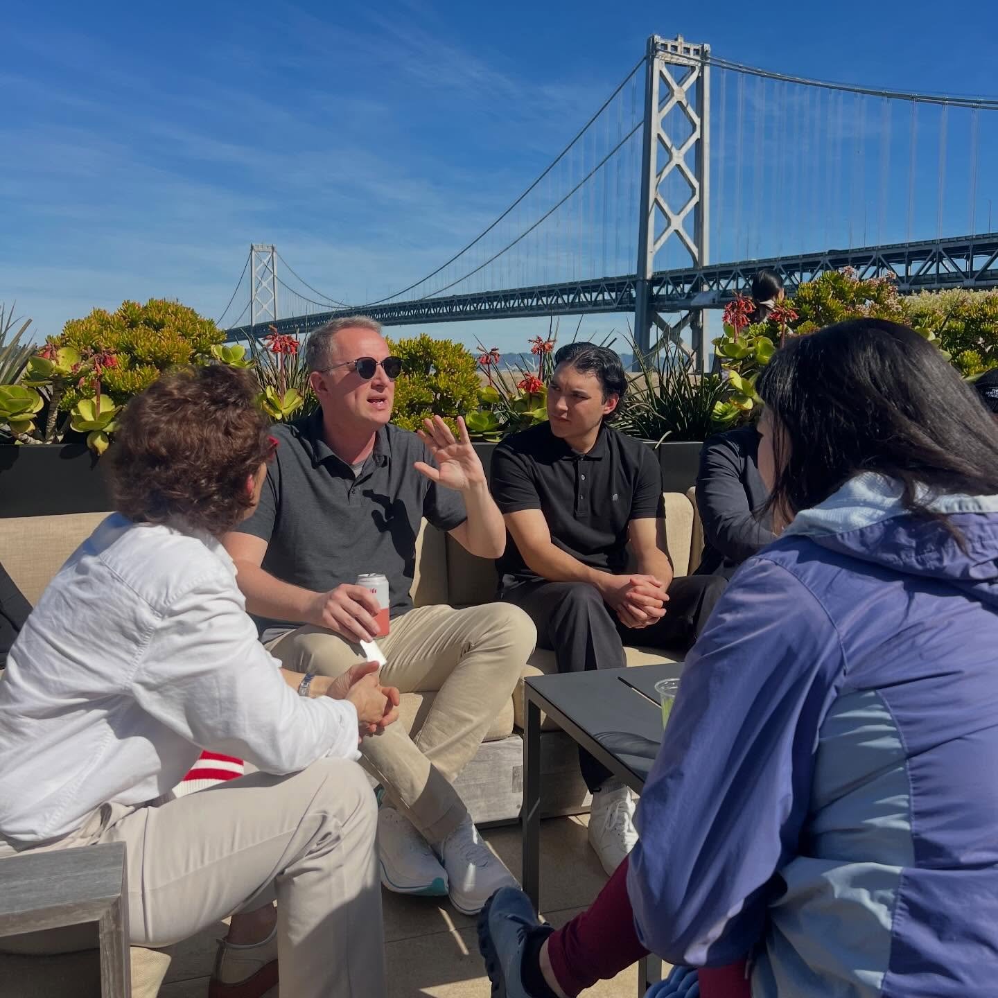 Officers and hosts talk on a terrace overlooking the Bay Bridge