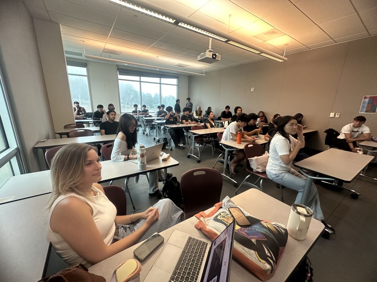 Members seated at tables in a classroom, listening to the presentation